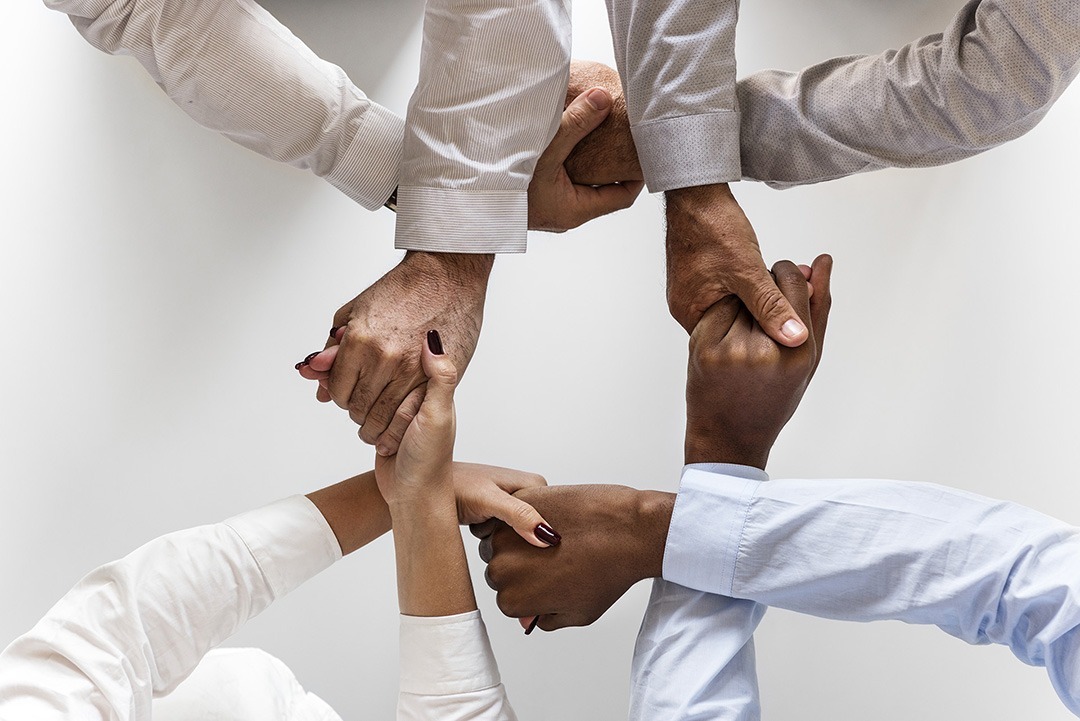 Corporate team members' hands joined together to symbolize teamwork and collaboration.