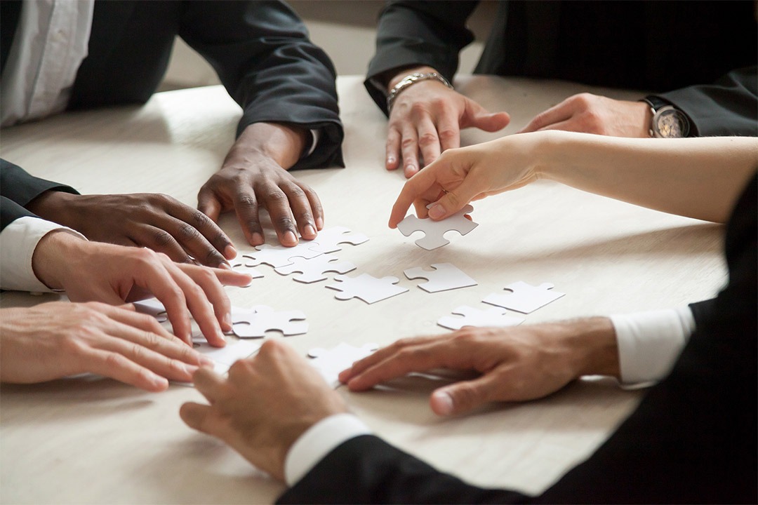 A close up of multiethnic corporate team solving blank puzzle game.